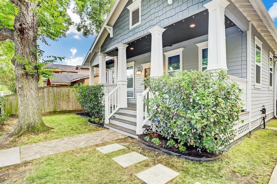 Historic Houston Heights craftsman bungalow exterior renovation featuring slate blue shingle siding, crisp white tapered porch columns, recessed porch lighting, and fresh landscaping by Square 1 Home Solutions.