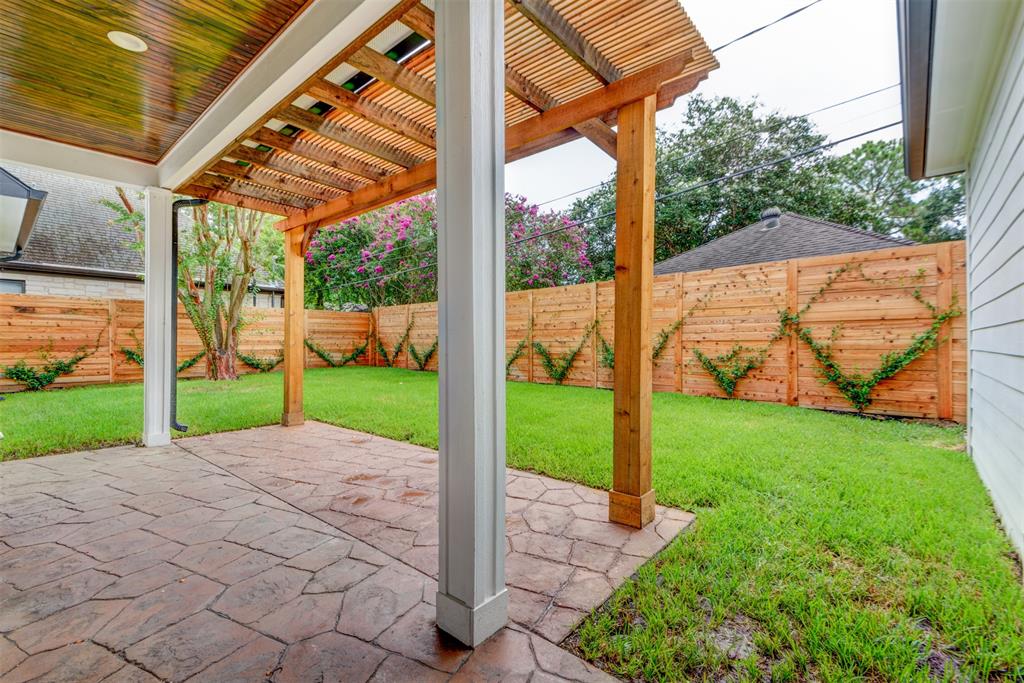 Custom covered patio and wooden pergola extension with stamped concrete flooring, stained wood ceiling, and manicured backyard built by Square 1 Home Solutions in Houston.